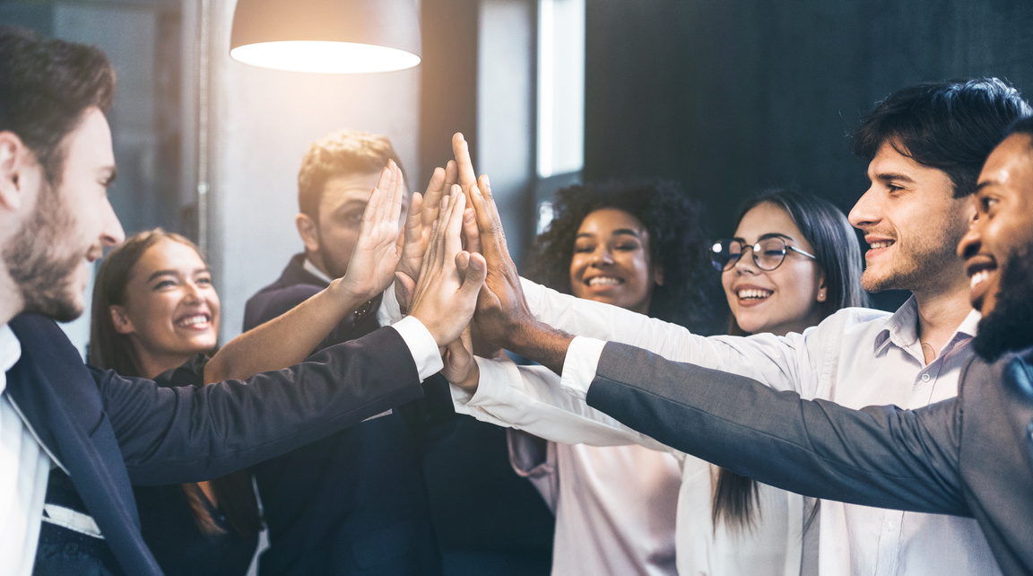 Happy office workers giving high five at meeting