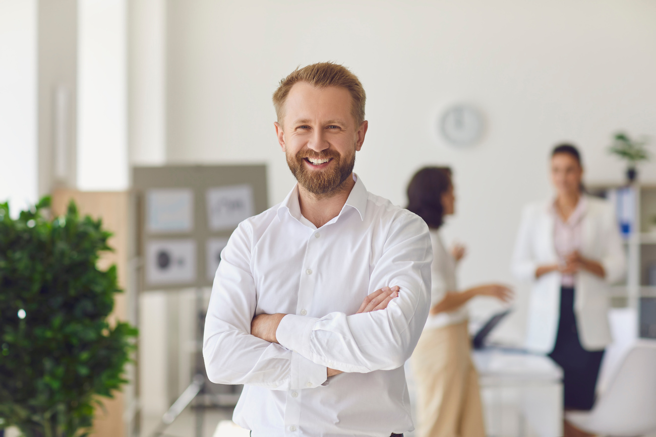 Happy Successful Businessman or Company Employee Standing in Office Looking at Camera